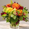 Mixed bouquet of orange and yellow roses with green orchids in a glass vase