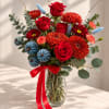 Bouquet of red roses and orange chrysanthemums in a glass vase with a red ribbon