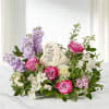 Pink and lavender floral tribute with a memorial stone centerpiece
