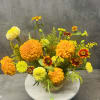 Orange and yellow marigold arrangement in a round vase