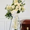 White funeral spray on an easel beside a casket