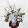 White floral arrangement with lilies and roses in a pale vase