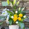 Potted peace lily with yellow roses and white tulips in a white container with ribbon.