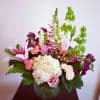 Mixed bouquet of pink lilies, roses, hydrangea, and snapdragons in a round glass vase