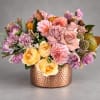 Mixed pink, yellow, and purple flowers arranged in a copper vase