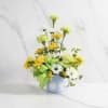 Yellow and white daisy bouquet in a blue mug with a green polka-dot bow