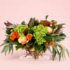 Orange and peach roses with green hydrangeas in a clear glass vase