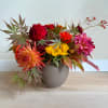Colorful mixed flower arrangement in a round gray vase