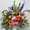 Large mixed flower arrangement in a white vase with orange gerberas and pink lilies