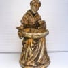 Wooden monk statue holding a shallow bowl with a bird and rabbit