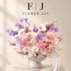 Pink and white floral arrangement with purple accents in a pedestal vase