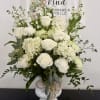 White roses and hydrangeas arranged in a white vase with greenery