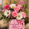 Pink and white bouquet in a pink mug with a heart ribbon