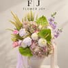 Pastel floral arrangement in a white vase with pink, white, and purple blooms.