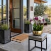 Orchid arrangement in a gold bowl on a concrete table outside a modern home