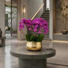 Purple orchids in a gold vase on a round table