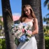 Woman in a white dress holding a large pastel bouquet outdoors