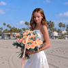 Woman in a white dress holding a bouquet of peach roses
