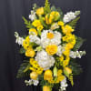 Tall standing spray of yellow roses, white hydrangeas, and yellow daisies on a green easel.