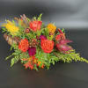 Autumn floral arrangement with orange roses and gourds in a woven basket