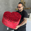 Heart-shaped box of red roses held by a man in sunglasses