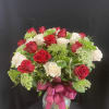 Red and white roses in a glass vase with a pink ribbon