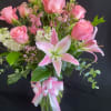 Pink roses and lilies in a glass vase with a pink ribbon