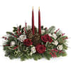 Holiday centerpiece with red candles, roses, and pinecones