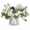 White floral arrangement in a clear glass vase with pinecones