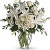 White lilies and roses arranged in a clear glass vase