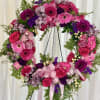 Heart-shaped floral wreath with pink and purple flowers on a stand