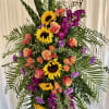 Tall standing floral spray with sunflowers, roses, and purple blooms