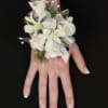 White floral wrist corsage with ribbon on a person's hand