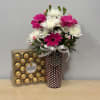 Pink and white flowers in a polka-dot vase beside a box of chocolates
