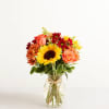 Bouquet of sunflowers, roses, and daisies in a glass vase