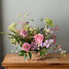 A charming basket arrangement filled with fresh seasonal blooms and garden-inspired textures.