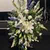 Tall white and blue floral standing spray on an easel