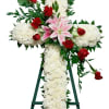Cross-shaped floral tribute with white blooms, red roses, and pink lilies on an easel