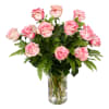 Pink and white roses in a clear glass vase with fern foliage