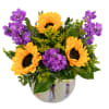Sunflowers and purple flowers arranged in a glass vase