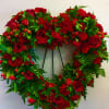 Heart-shaped wreath of red roses and carnations on a stand