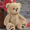 Teddy bear beside a vase of pink flowers