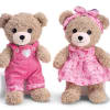 Two teddy bears in pink outfits, one in overalls and one in a dress