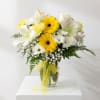 Yellow and white bouquet in a glass vase with a yellow ribbon