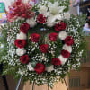 Standing floral wreath with red and white roses and a white lily