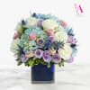 Bouquet of pastel roses and hydrangeas in a blue glass vase