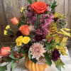 This stylish floral arrangement features a contemporary ceramic pumpkin as its base