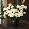 White roses arranged in a black hatbox with a ribbon