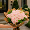 Bouquet of pale pink roses wrapped in brown paper with green leaves