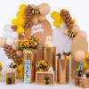 Birthday display with balloon arches, sunflowers, and a cake on gold pedestals